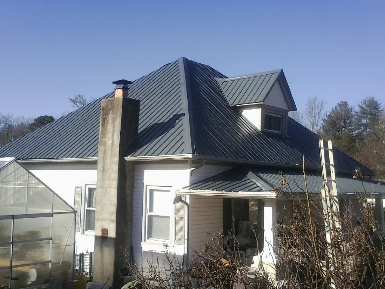 Dark blue standing seam metal roof on a white farmhouse with dormer — Slate & Tile Roof Repair by Roofing Brothers in Thornville