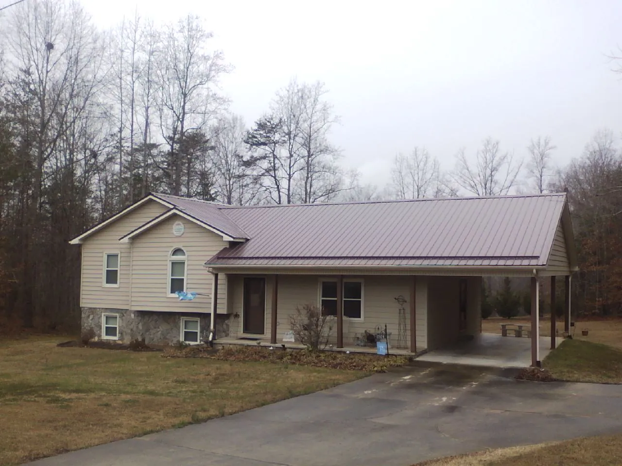 Burgundy metal roof on a tan split level home with an attached carport in Thornville