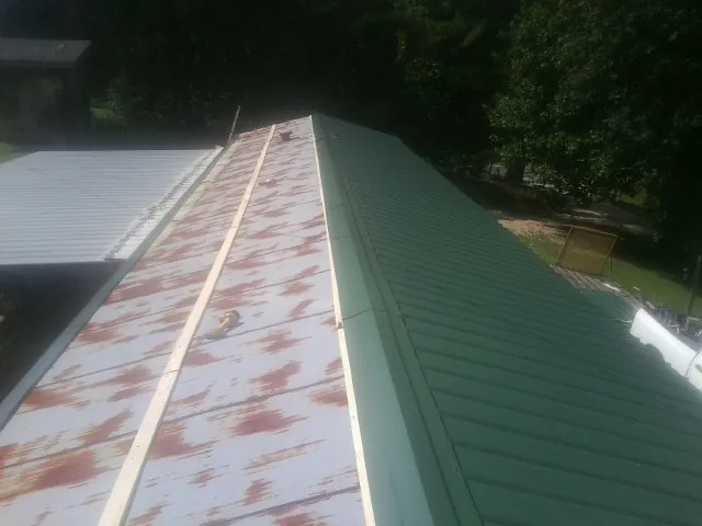 Old rusted panels beside newly installed green metal roofing — Wind Damage Roof Repair by Roofing Brothers in Thornville