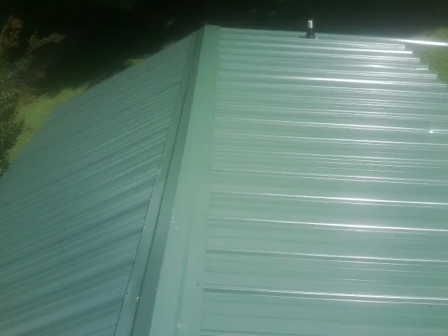 New green metal panels meeting at the ridge of a roof — Flat Roof Repair work by our crew in Thornville