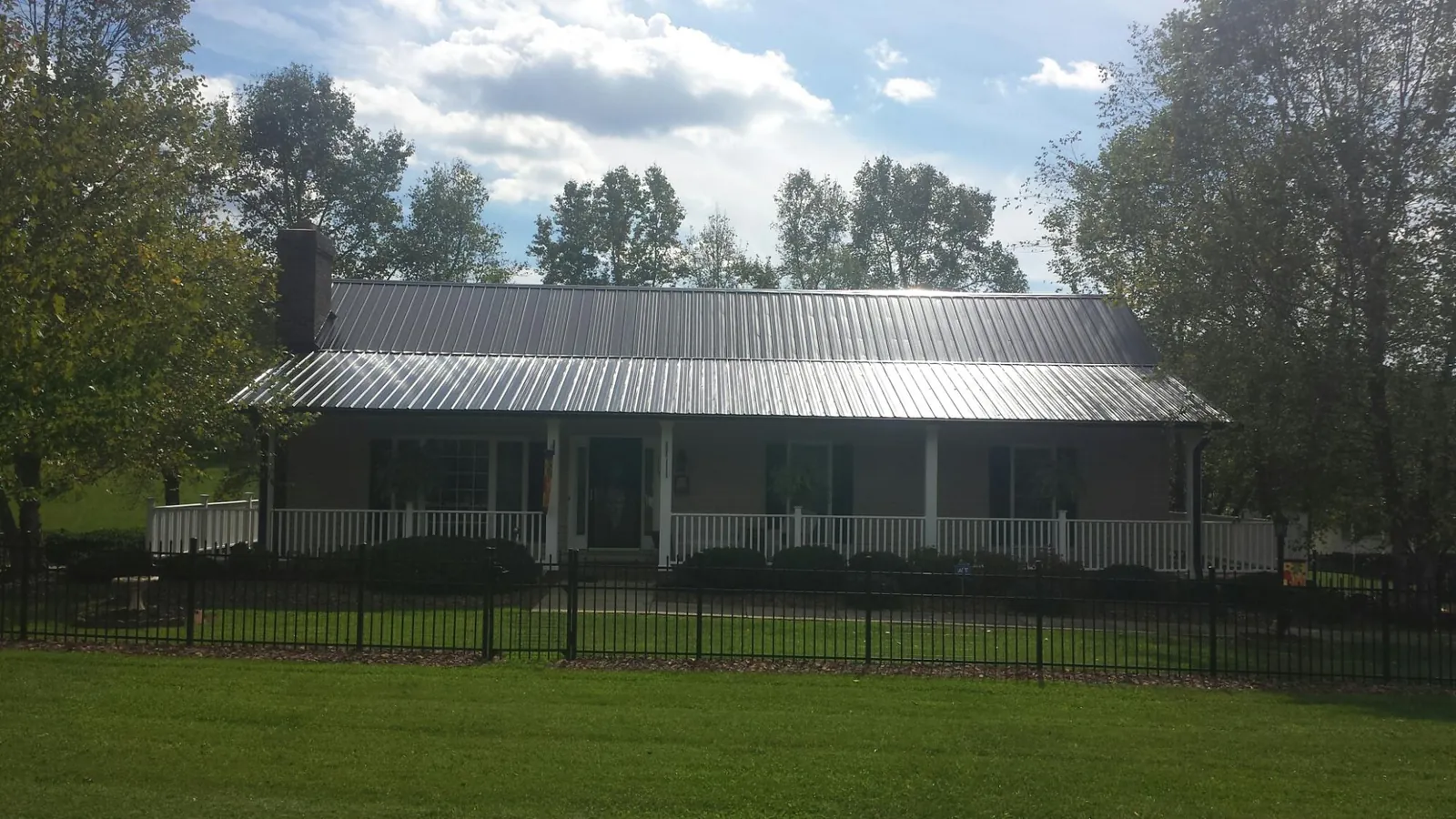 Gray metal roof on a brick ranch with a full width front porch — Gutter Guard Installation work by our crew in Thornville