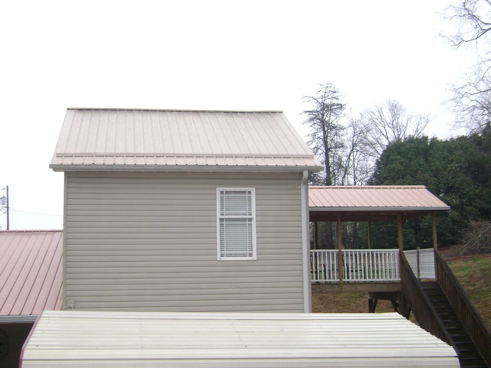 Tan metal roofs on a two story addition and attached porch, from a Roof Replacement job in Thornville