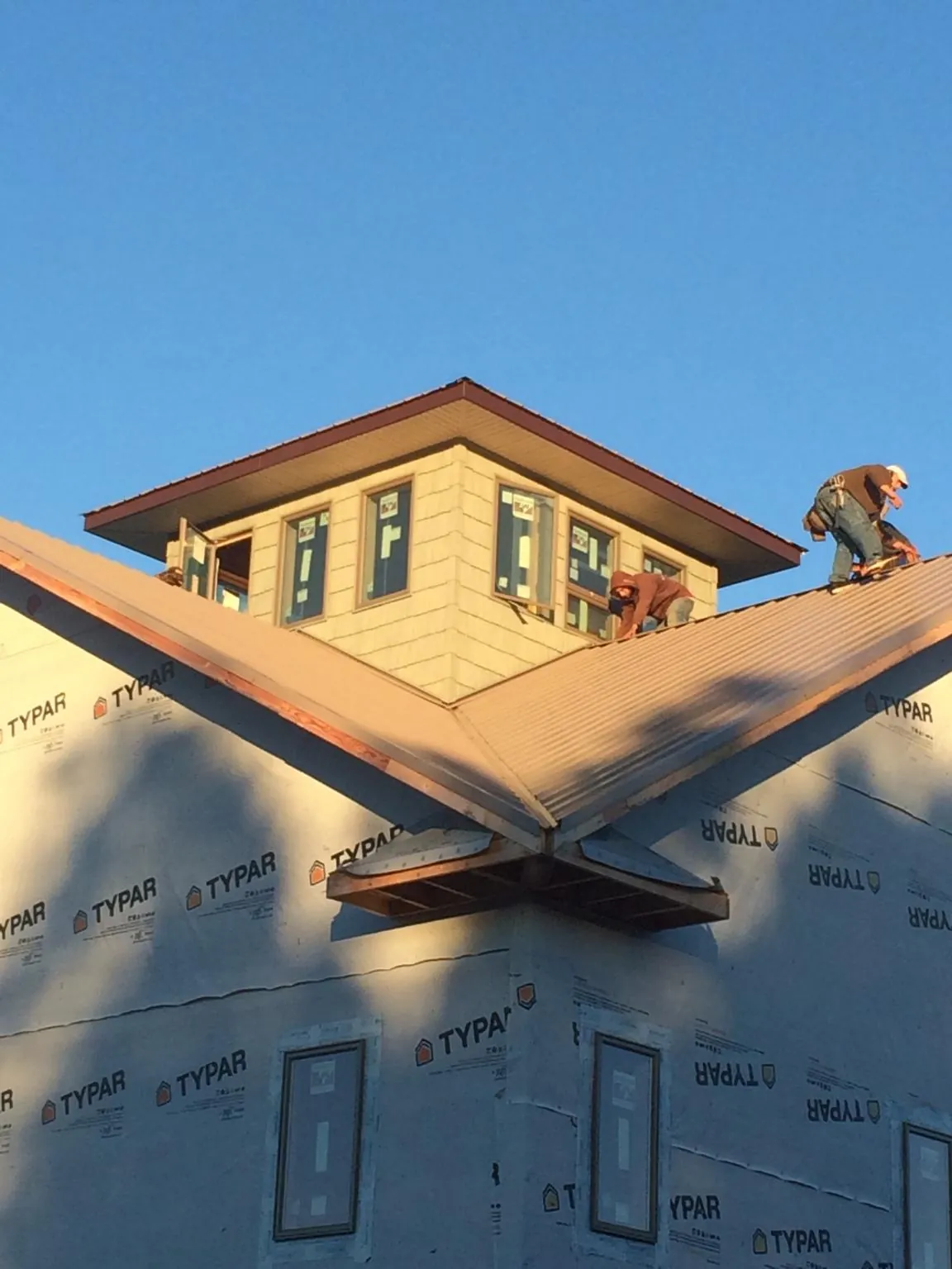 Roofers working around a rooftop cupola on a new metal roof at sunset — Roof Waterproofing in Thornville by Roofing Brothers